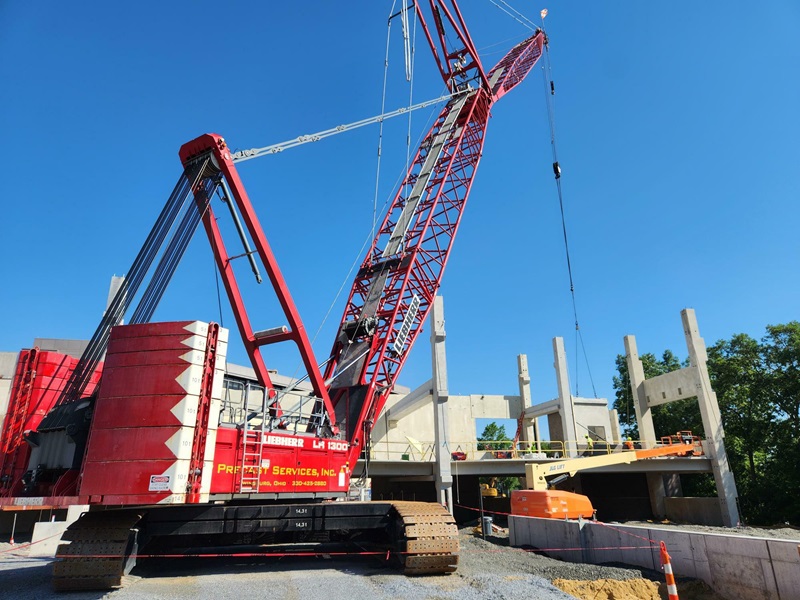 A ground view of a red crane and a garage structure.