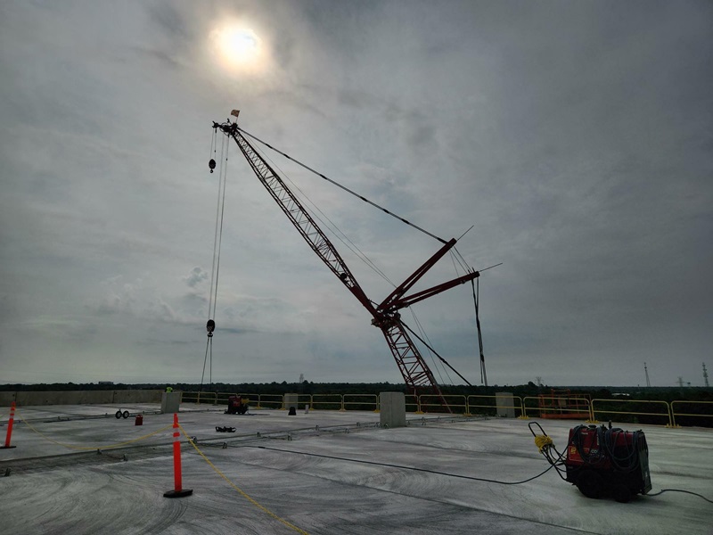 A darker view of a red crane from a rooftop.